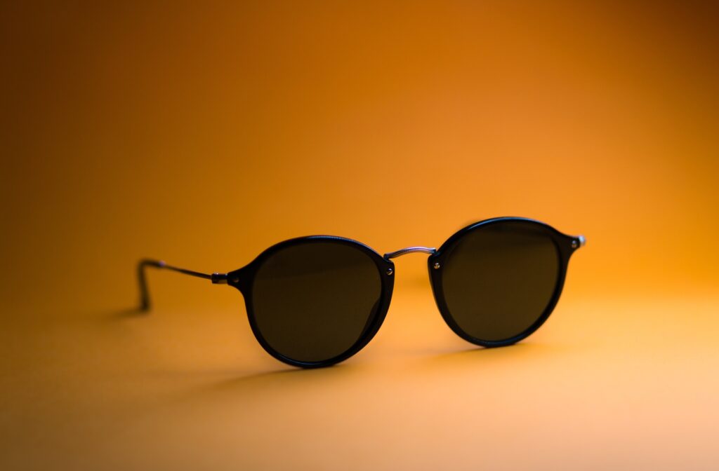 Fashionable black pair of round sunglasses sitting on an orange background.