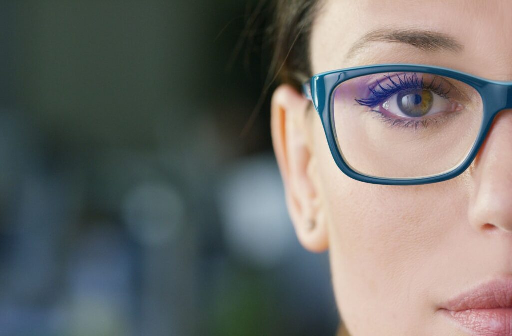 A close up image of a woman's face and she is wearing blue glasses