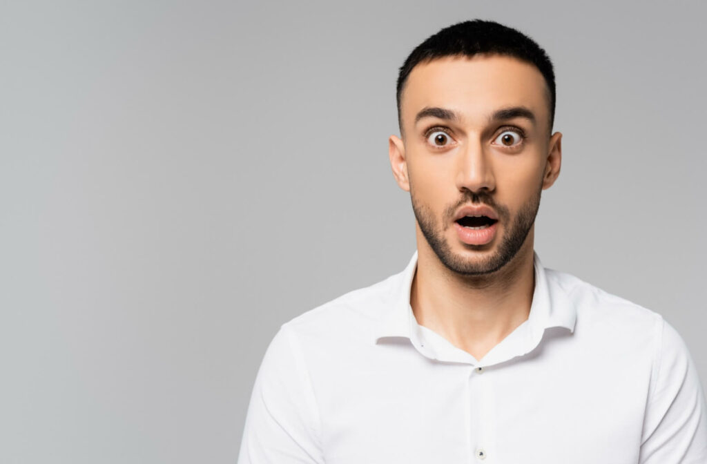 Young hispanic man with wide, building eyes--one of the symptoms of Grave's disease.