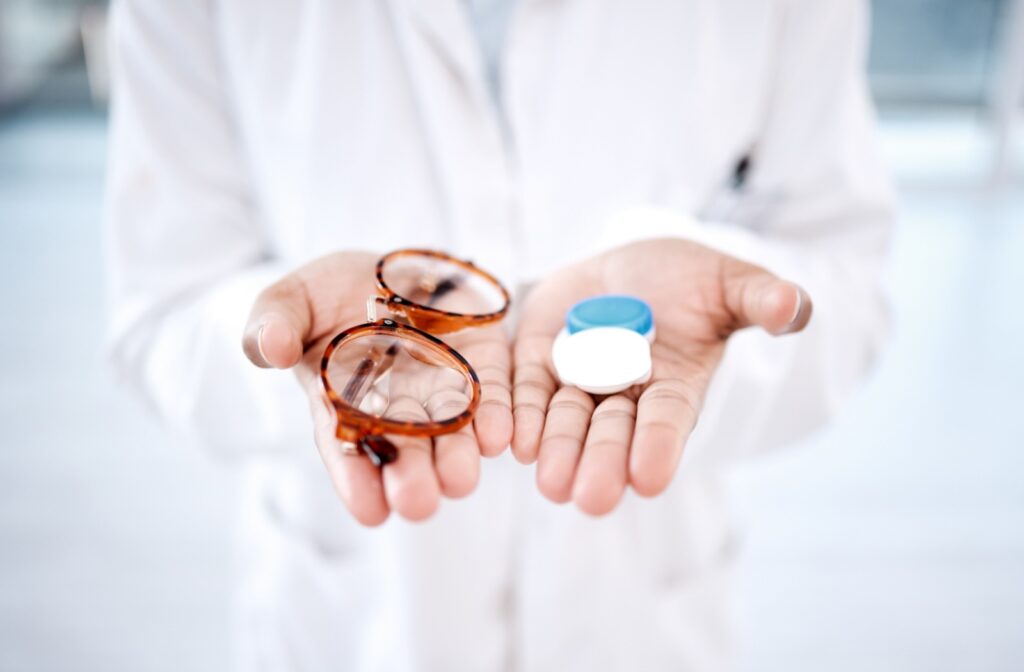 Optometrist holding a pair of glasses in one hand and contact lens case in the other.