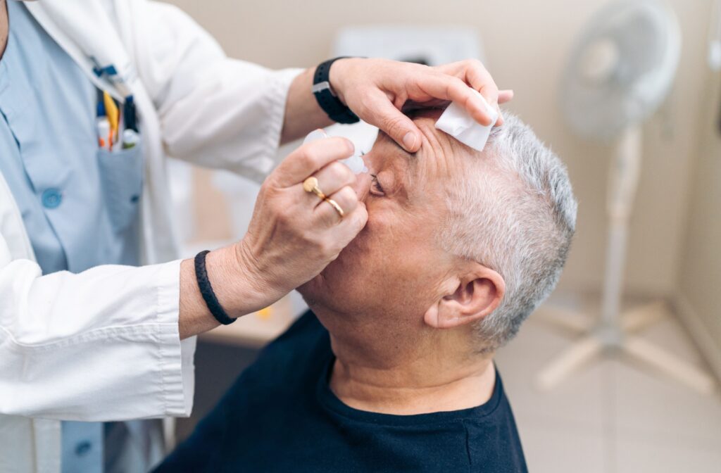 An eye doctor applying eye drops to a man's eye during an examination,