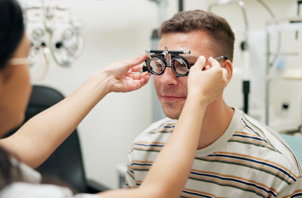 Optometrist adjusting a phoropter during an eye exam for a male patient.